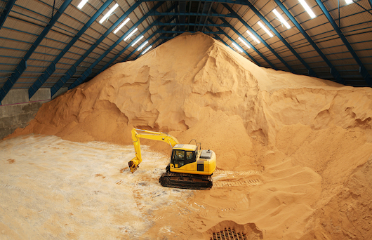Excavator in a raw sugar storage