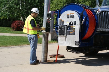 A Clean-Co employee cleans a storm drain with a jet rodder.